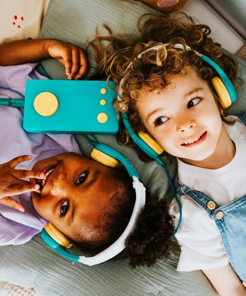 Deux enfants écoutant avec un casque sur la tête des histoire de Ma fabrique à histoire fabriqué en France par Lunii.