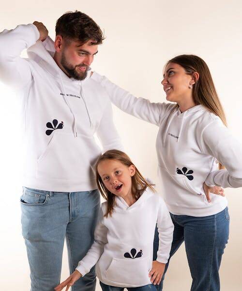 Un père et ses deux filles en jeans bleus et portant des sweats blancs fabriqués en France de la marque Maison Tricolore.