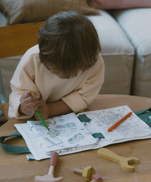 Enfant brun dessin sur son carnet de coloriage fabriqué en France par La nature des petits.