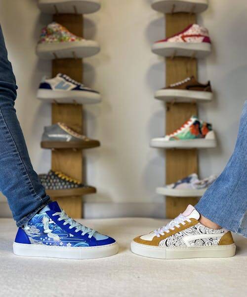 Deux baskets de la marque Uniqua Limoges avec motifs coloré bleu et beige se sont face devant un promontoire rempli de baskets stylés et originales.