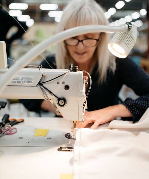 Femme entrain de coudre un drap Made in France de la marque A demain.