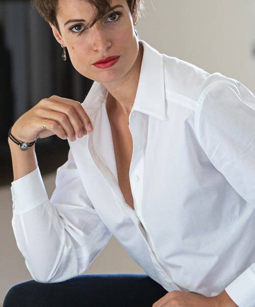 Femme brune portant une chemise blanche coupe ajouté fabriqué en France par Sénovie.