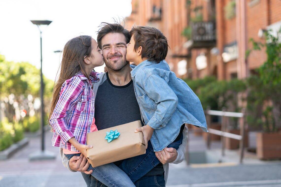 Papa recevant un bisous et un cadeau Made in France de la part de ses enfants.
