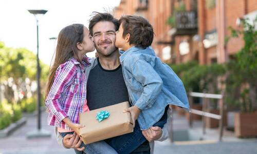 Papa recevant un bisous et un cadeau Made in France de la part de ses enfants.