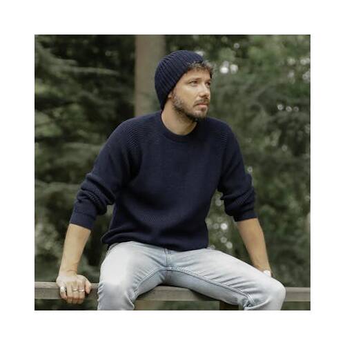 Homme portant un pull marine et un bonnet bleu.