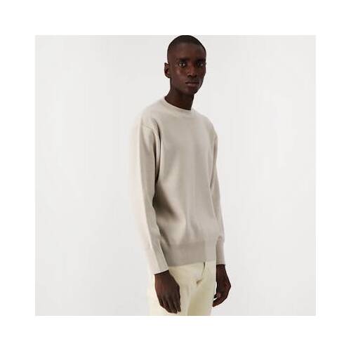 Homme portant un pull écru et un jean blanc.