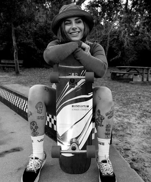 Photo noir et blanc d'une skateuse accoudée sur son skate fabriqué en France par Trashboard.