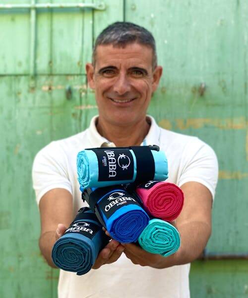 Photo du fondateur de la marque ÔBABA portant des draps de plage fabriqués en France.