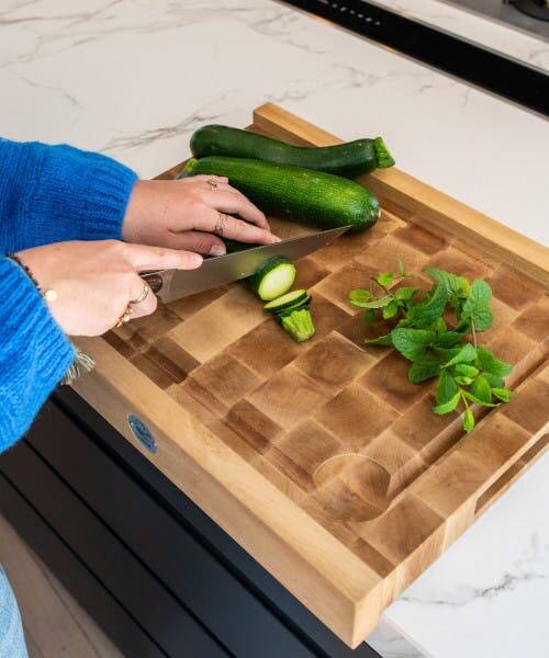 Femme entrain de découper des courgettes sur un billot en bois de bout fabriqué en France par Chabret.