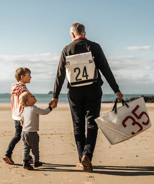 Père, avec ses deux enfants, portant un sac à dos et un cabas Vente de Voyage Made in France.