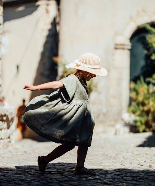 Jeune fille portant un chapeau de paille et un robe verte fabriquées en France par Epiko.