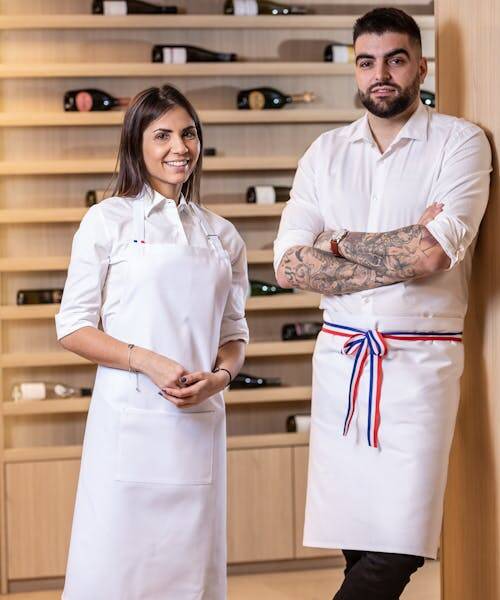 Une homme et une femme portant des tabliers blancs fabriqués en France par Création Talbot.