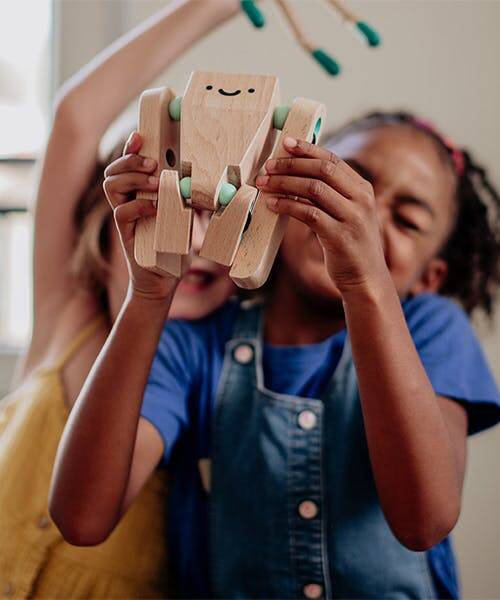 Enfant jouant avec un robot en bois fabriqué en bois par  l'Atelier de la belle étoile.