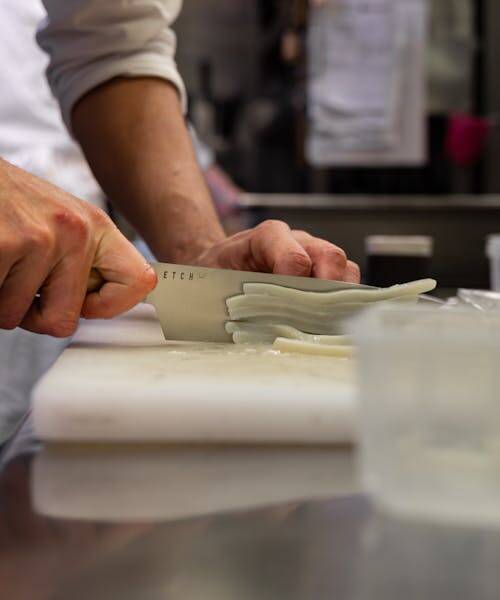Cuisinier entrain de découper avec un couteau de chef français  de la marque ETCH .