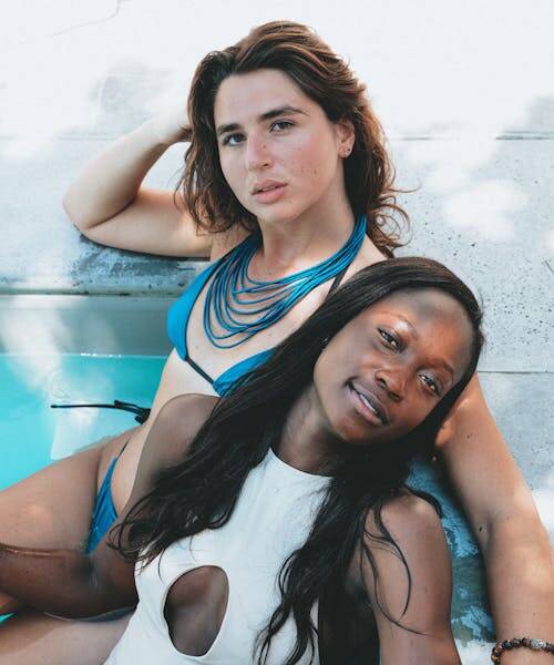 Deux femmes portant un maillots de bain une pièce blanc et un maillot deux pièces bleus fabriqués en France par Khiónê.