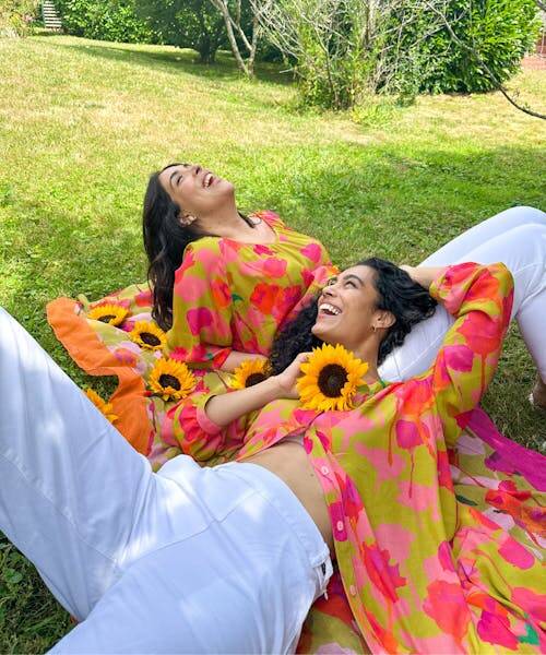 Deux femmes allongées sur le gazon portant deux blouses avec motifs imprimés fabriquées en France par Made in France.