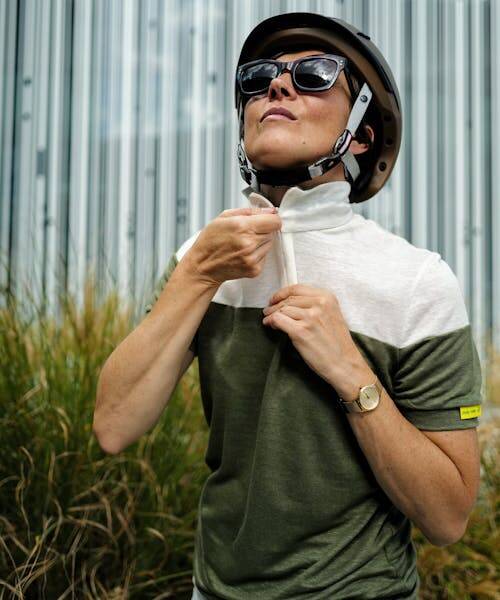 Photo d'une cycliste, portant un casque de vélo, en train de zipper son polo en lin fabriqué en France.