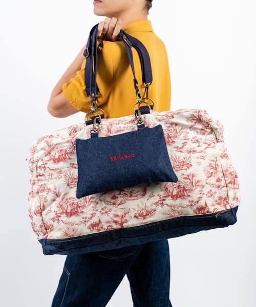 Femme brune portant un sac à main et un sac de voyage Made in France fabriqué par Béhabag.