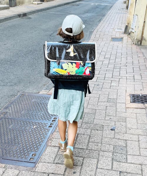 Enfant portant un cartable noir fabriqué en France par la marque Piolou.