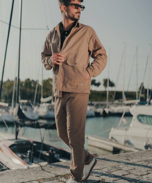Homme brun portant une veste et un pantalon beiges fabriqués en France par Rue Begand.