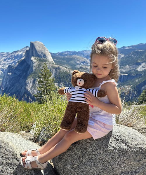 Jeune fille portant sa peluche nounours fabriqué en France par Les Petites Maries.