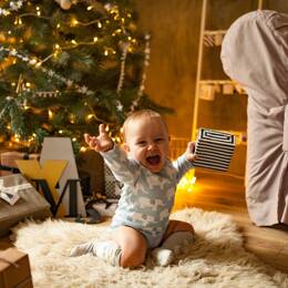 Bébé découvrant avec joie son cadeau made in France près du sapin de Noël. 