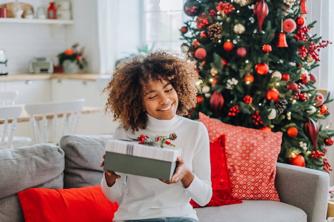 Femme recevant un cadeau Made in France devant un sapin de Noël.
