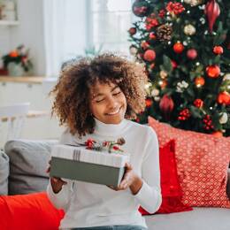 Femme recevant un cadeau Made in France devant un sapin de Noël.
