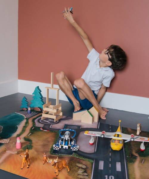 Enfant jouant sur un tapis de jeu Carpeto et sa piste de décollage.