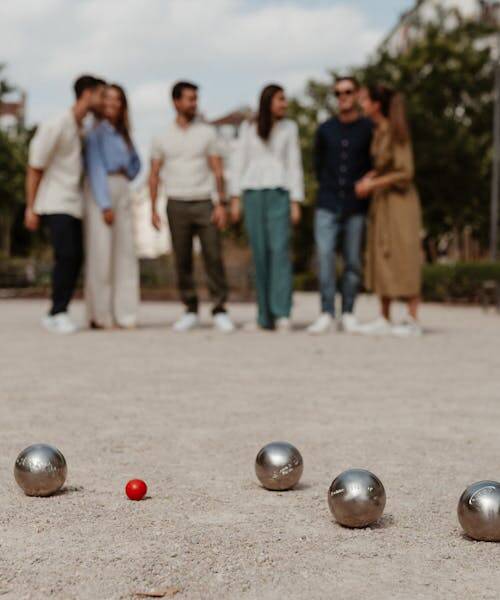 Groupe d'amis entrain de jouer avec des boules de pétanques fabriqués en France par Obut.