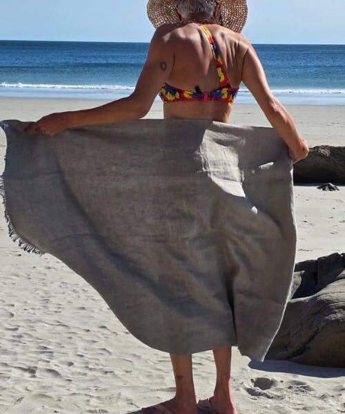 Femme sur la plage avec un fouta gris en lin fabriqué en France.