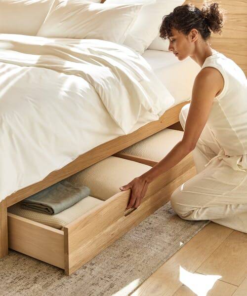 Femme ouvrant un tiroir de lit en bois fabriqué en France par la marque Kipli.