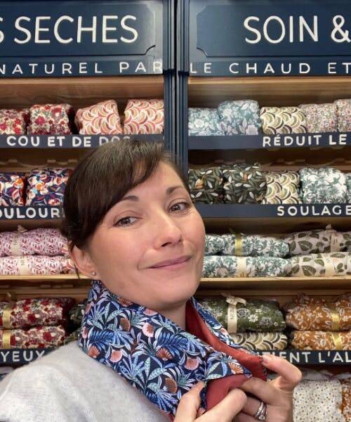 Marie, la fondatrice de N .ère atelier, posant devant son stand au Salon du Made in France et portant une bouillotte fabriquée en France.