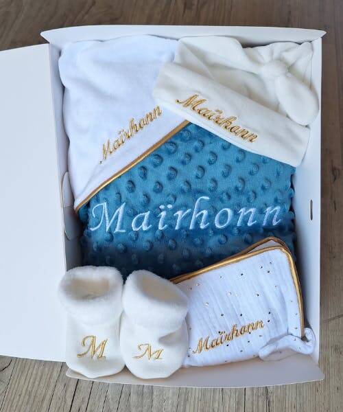 Coffre de Naissance bébé fabriqué en France par  La Fabrique À DeDeuh. Ce coffret contient : une cape de bain, des chaussons et un bavoir personnalisés avec broderie au nom de bébé.