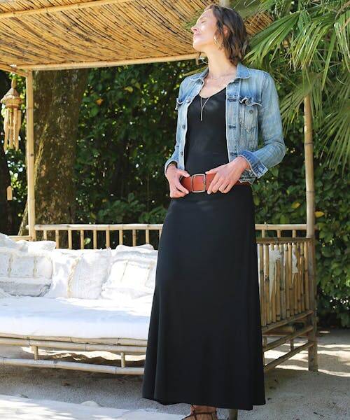 Femme portant la robe longue noire avec un col V fabriquée en France par Thelma & Rose.