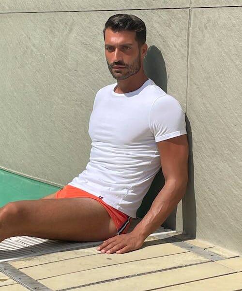 Homme portant un t-shirt Erverte blanc made in France et un slip de bain orange.