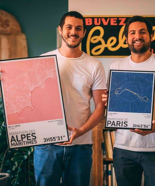Fondateurs de Sport à l'affiche portant deux cadres avec des affiches de Marathon fabriqués en France.