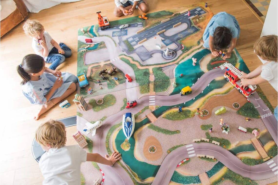 Enfants jouant avec leurs figurines et véhicules sur les tapis de jeu Made in France de Carpeto.